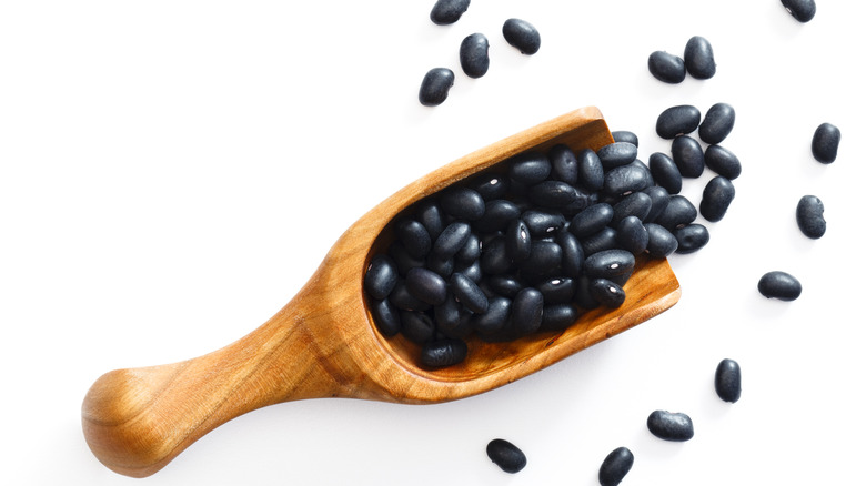 Top view of dry black beans on wooden spoon