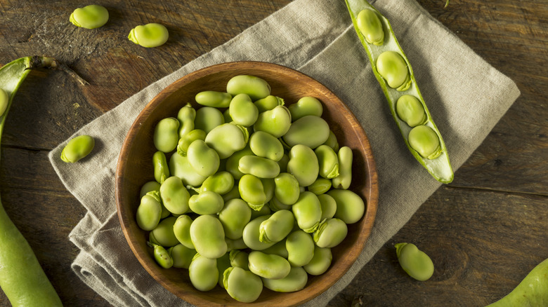 Top view of bowl with fava beans and fava beans in pods