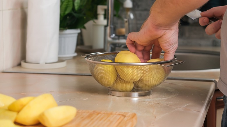 Hand preparing raw potatoes