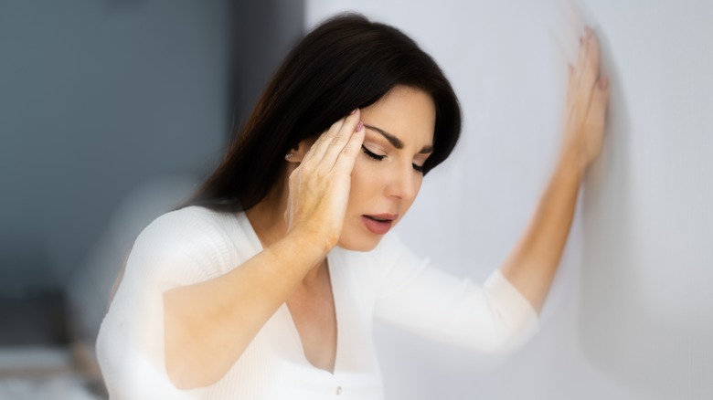 Woman holding ears leaning on wall