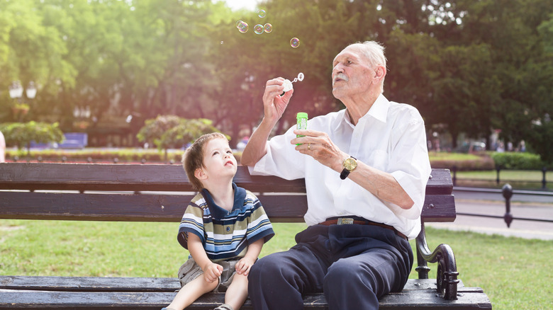 grandpa blowing bubbles for grandson on sunny day