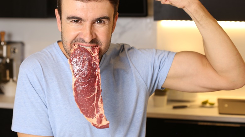 raw meat hanging from man's mouth