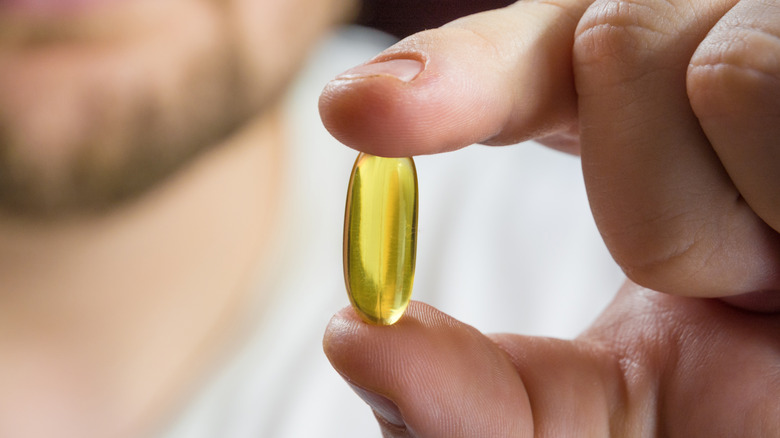man holding a fish oil pill