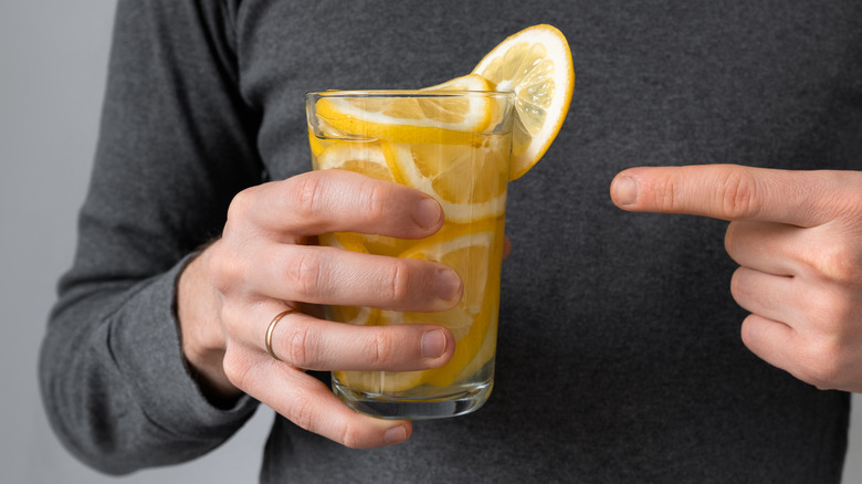 man holding glass of lemon-filled water