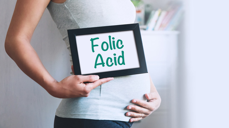 pregnant person with folic acid sign