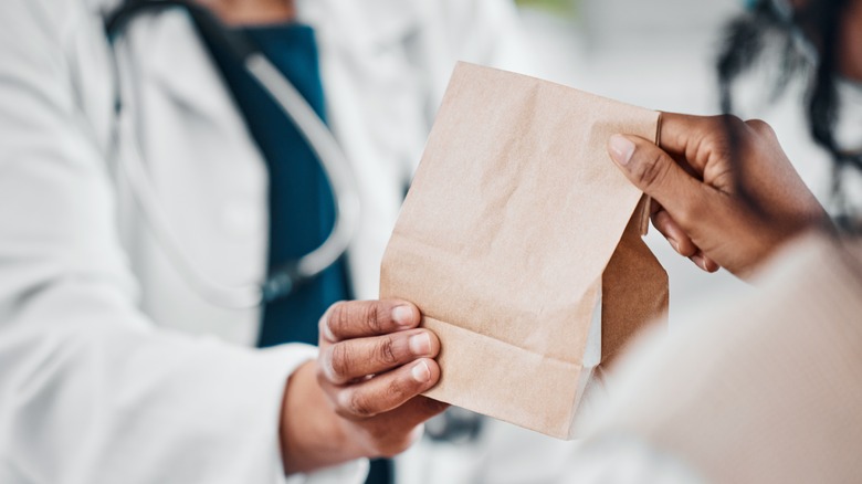 Pharmacist handing bag to patient