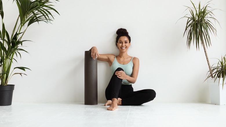 woman leaned on wall with Pilates mat