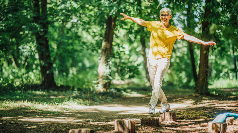 woman balancing on stump in forest