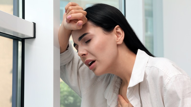 Woman with breathing problems leaning on a window