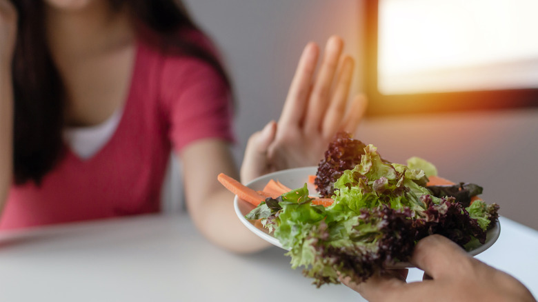 Woman gesturing that she doesn't want salad