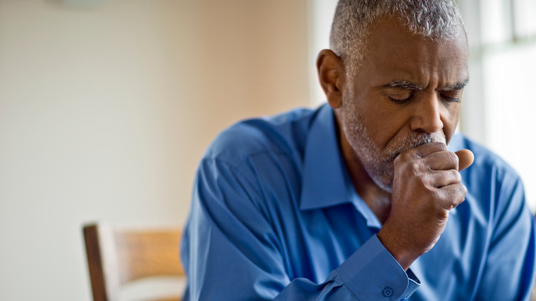 man coughing into closed fist