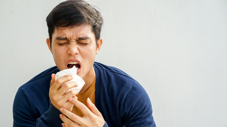 distressed man coughing into tissue