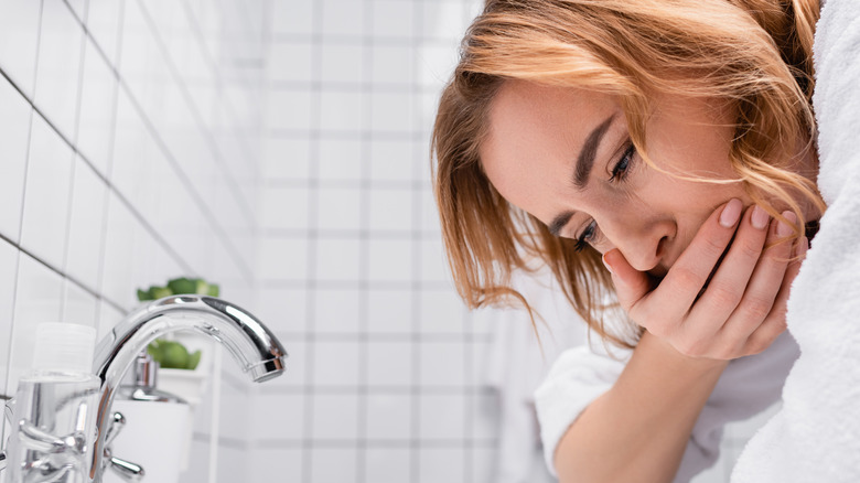 woman feeling nauseous in bathroom