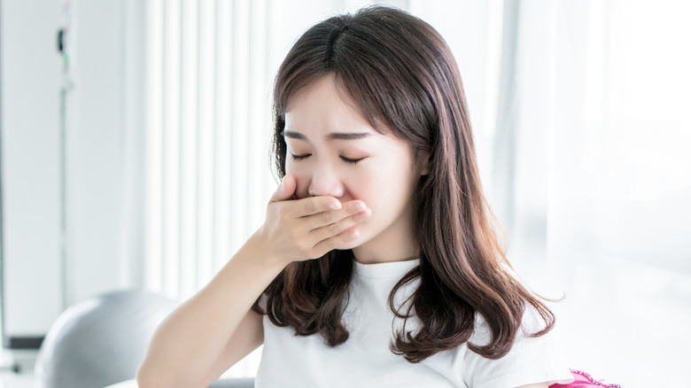 woman sitting on couch with nausea 