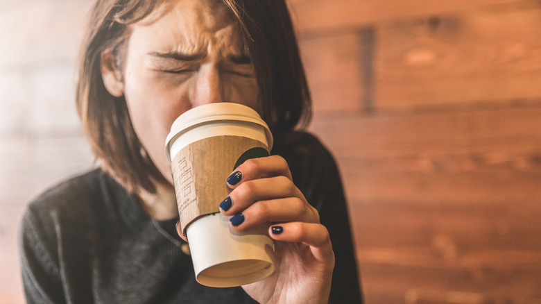 woman wincing from drinking hot coffee