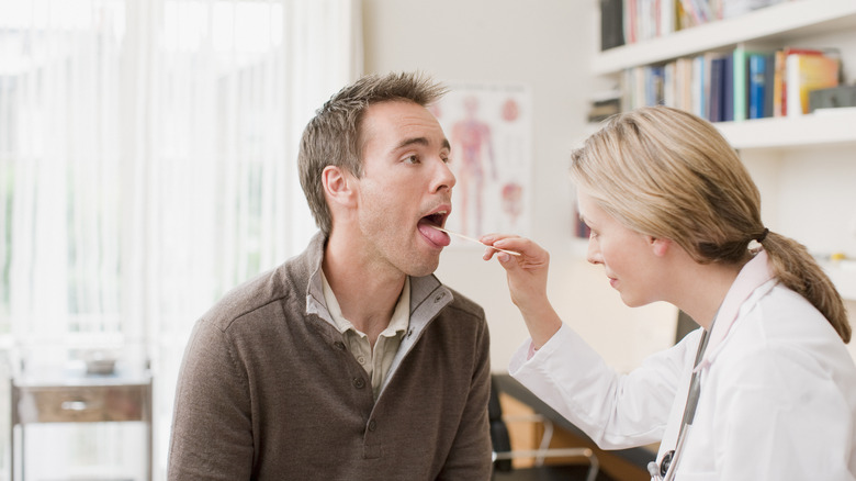 A doctor looking at a patient's tongue