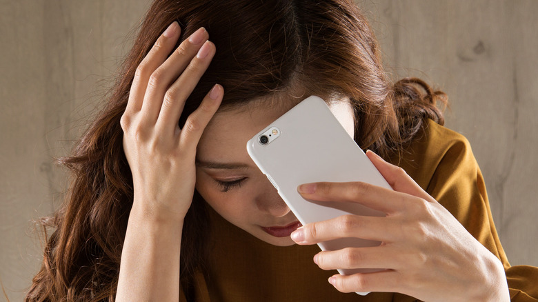 distressed woman holding her phone 