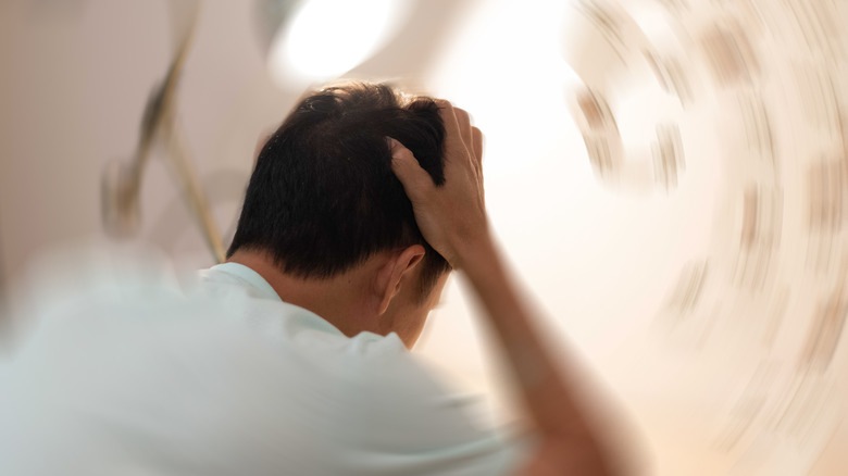 man holding head in blurry room