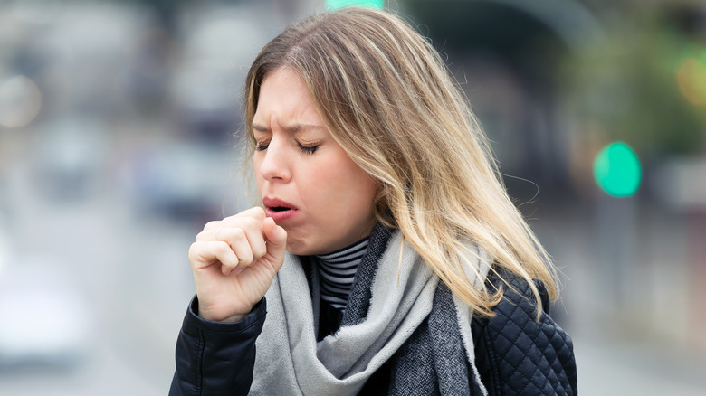 Woman coughing into her hand