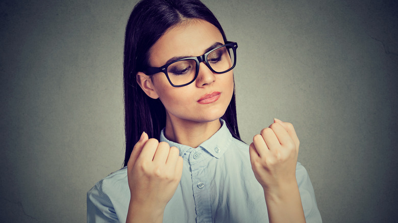 Woman in glasses looking intently at fingers