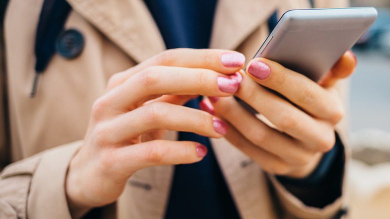 Person with manicured nails using a smartphone