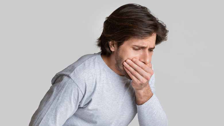 Man feeling nauseous with hand over mouth 