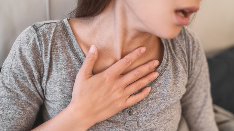 woman in gray shirt with hand to chest