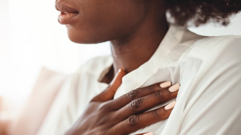 Woman holding chest and breathing