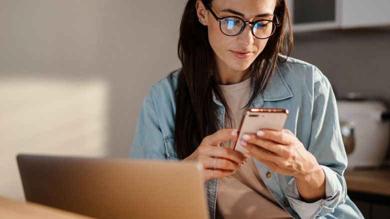 woman researching with phone and laptop