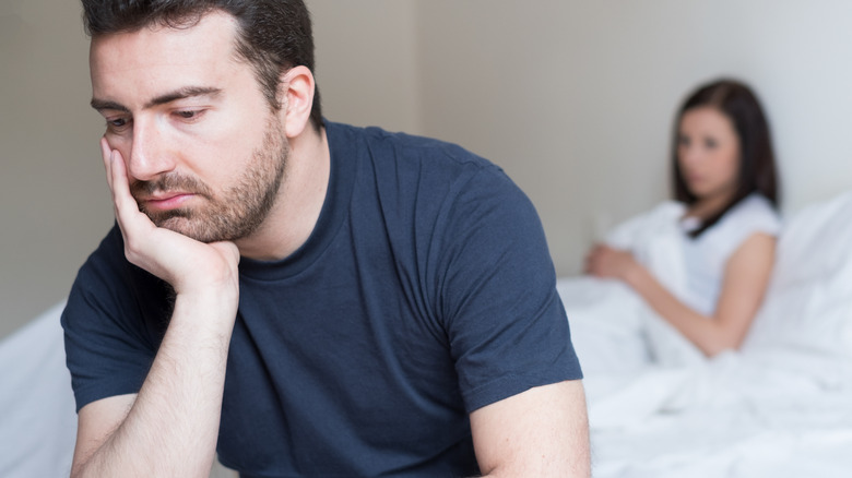 sad man backing woman in bed