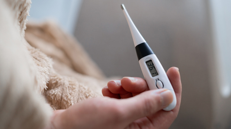 An over-the-shoulder shot of a man's hands looking at a thermometer