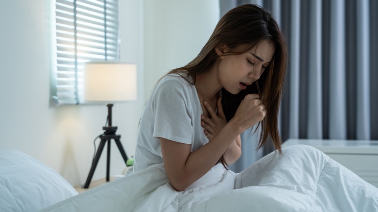 young woman siting up in bed catching her breath