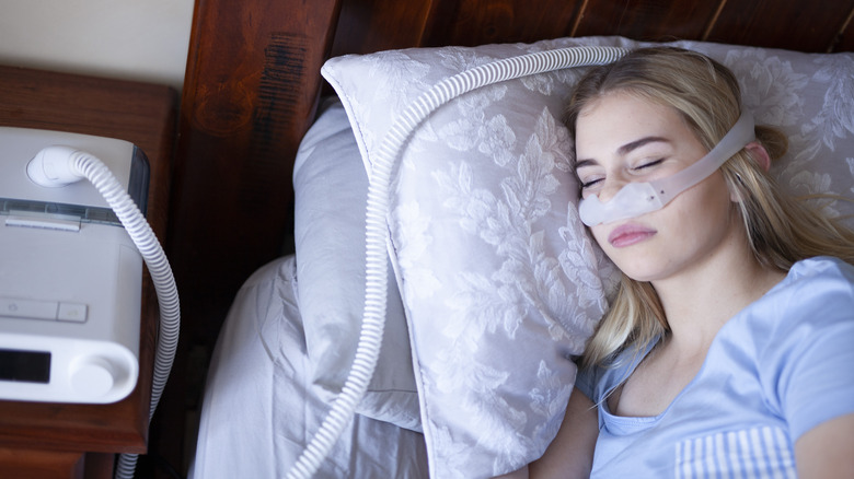 woman sleeping soundly with CPAP mask and machine