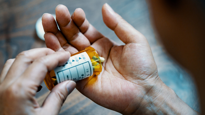 man putting prescription pills in his hand