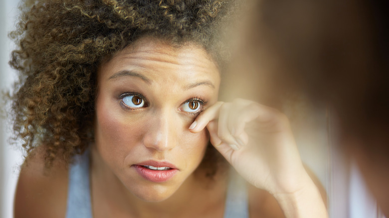 A woman examining her eye in the mirror