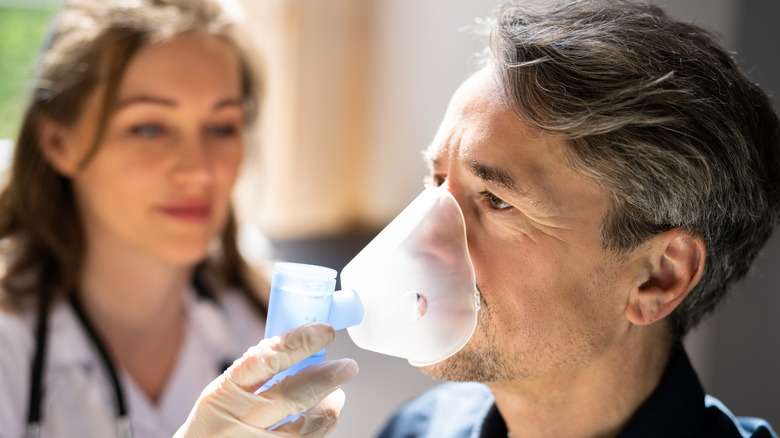 doctor helping man use nebulizer