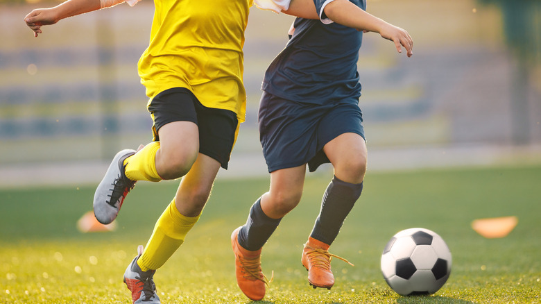 kids playing soccer in grassy field