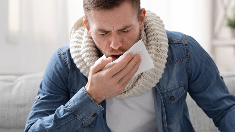 sick man coughing into napkin