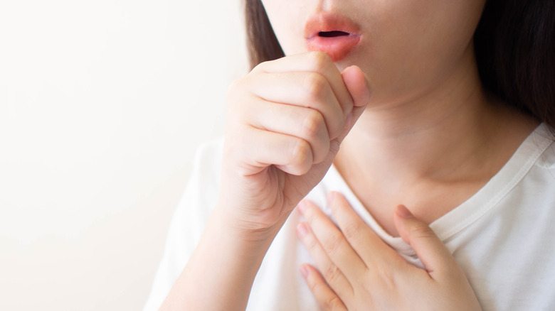 coughing woman with hand on chest
