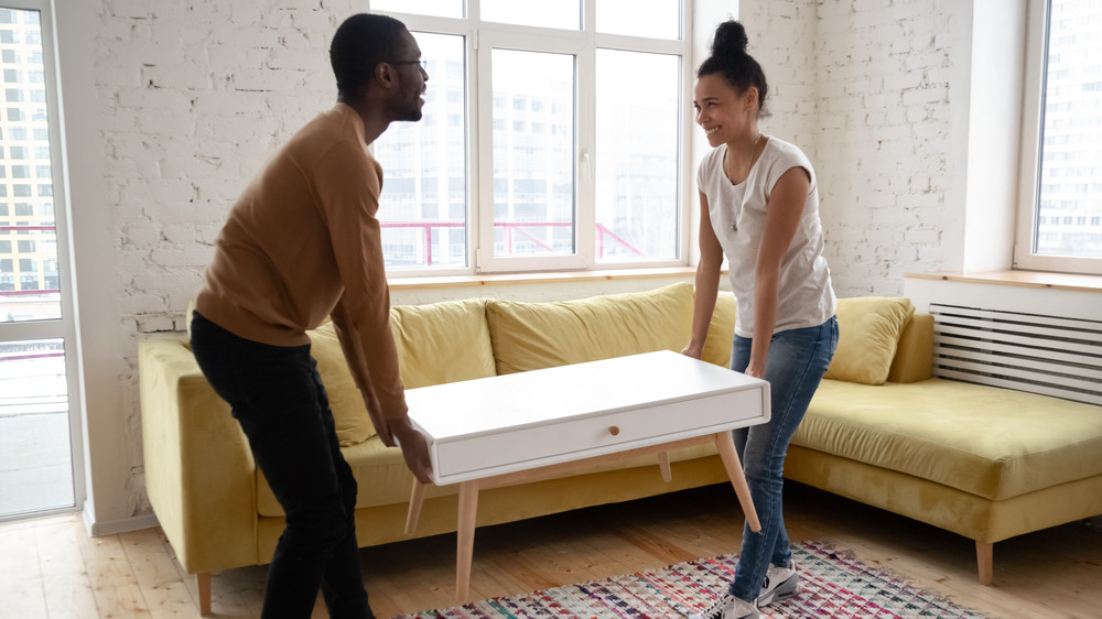 A smiling couple moving a piece of furniture