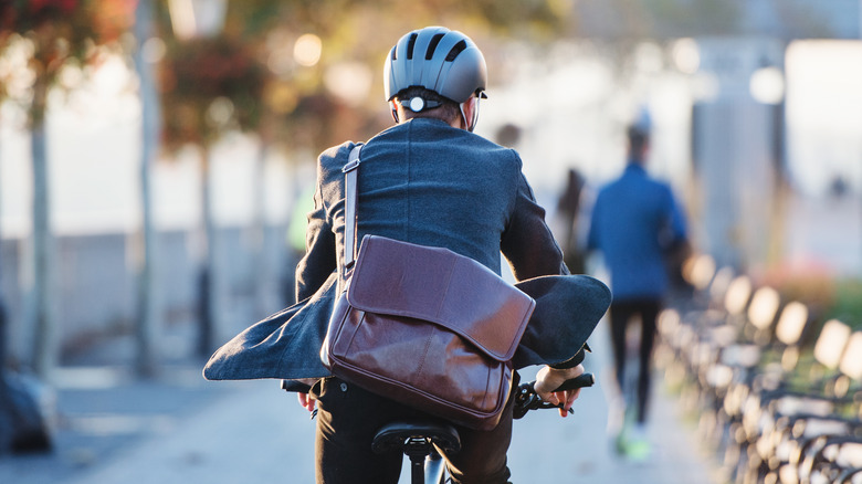 man riding bike to work with helmet and suitcase