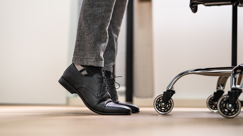 man on tip toes in office 