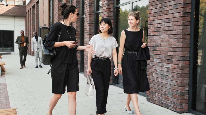 three women walking in work clothes outside 