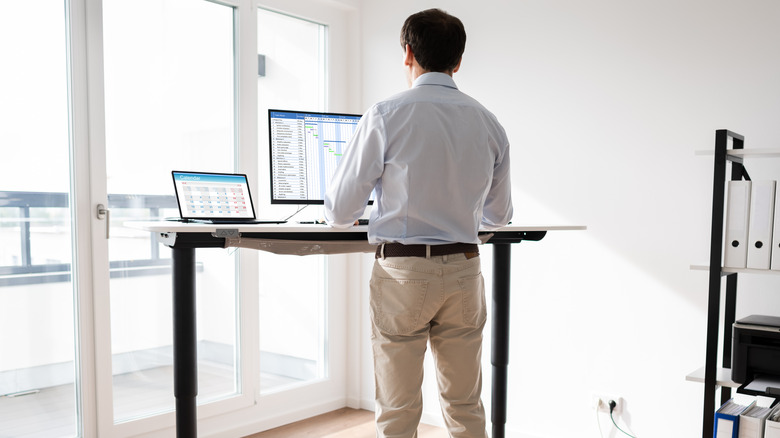 man standing at standing desk home office