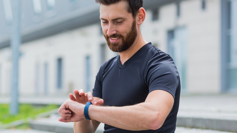 Man in workout shirt looking at wristwatch