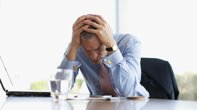 stressed out man holding his head in hands