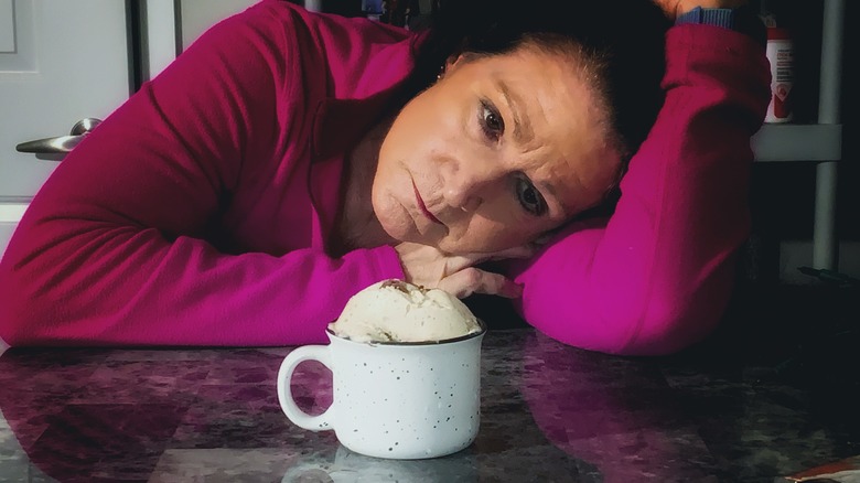 woman staring wistfully at a mug of ice cream