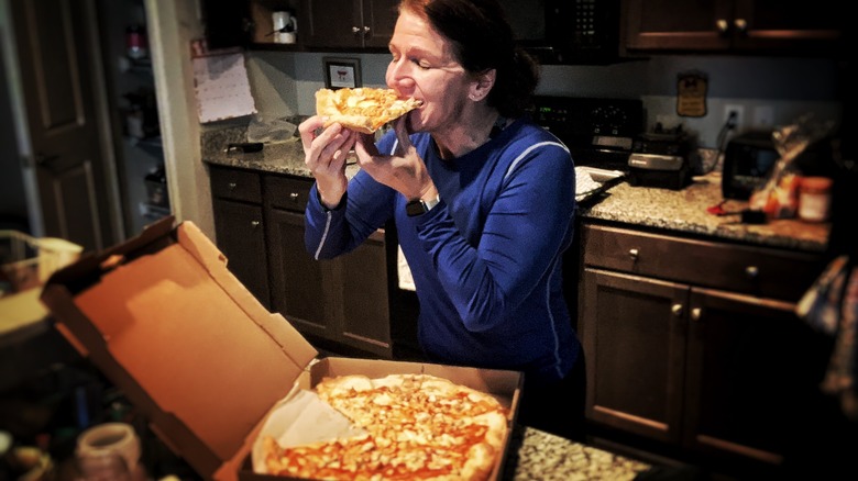 woman eating pizza in her kitchen