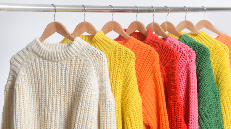 Colorful knitted sweaters hanging on a rack