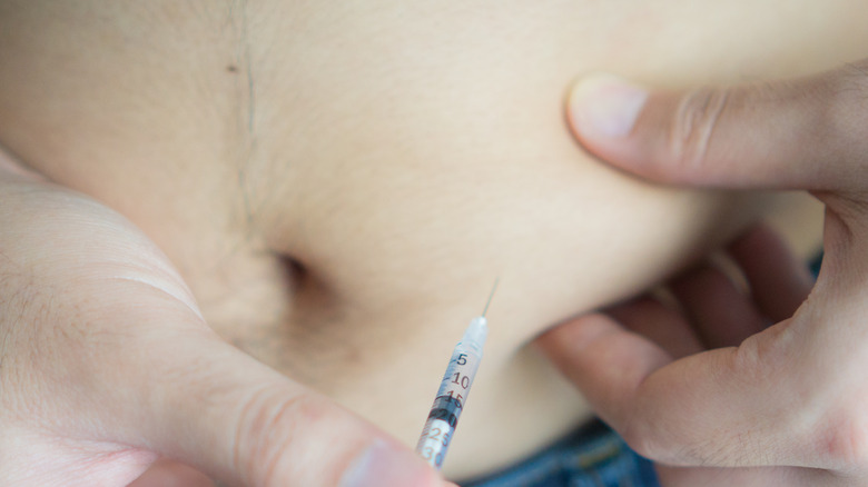 man injecting medicine in abdomen